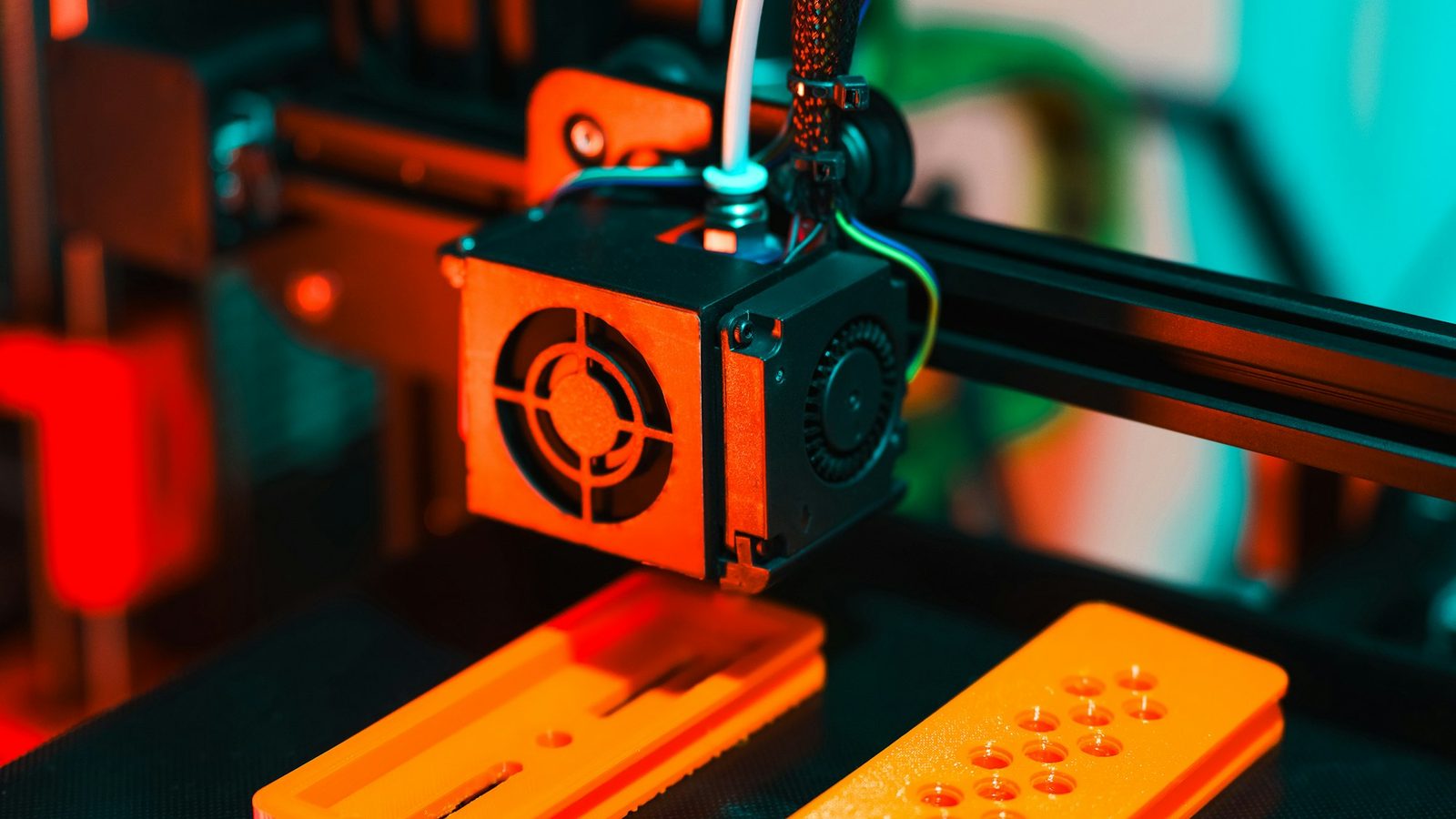 FDM printer laying orange parts on the bed